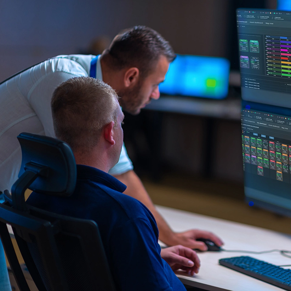 Group of Security data center operators (administrators) working in a group a monitoring room while looking at multiple SCADA monitors