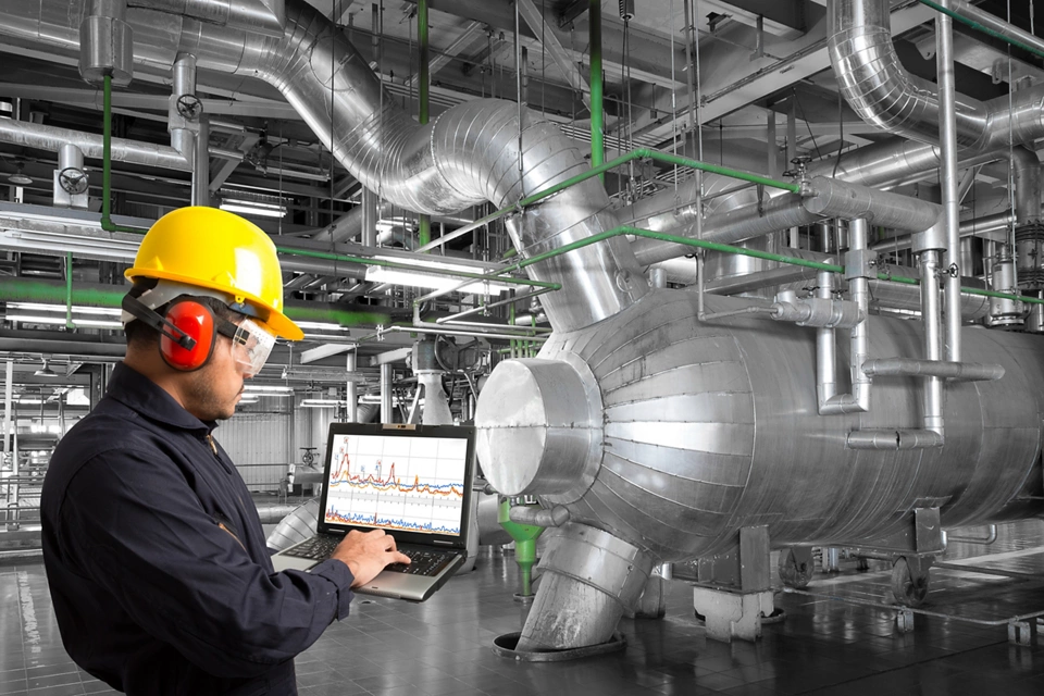 Engineer monitoring industrial equipment with laptop