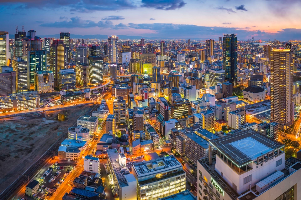 The glittering lights, neon night, soaring skyscrapers and zooming highways of the futuristic crowded cityscape of central Osaka, Japan.