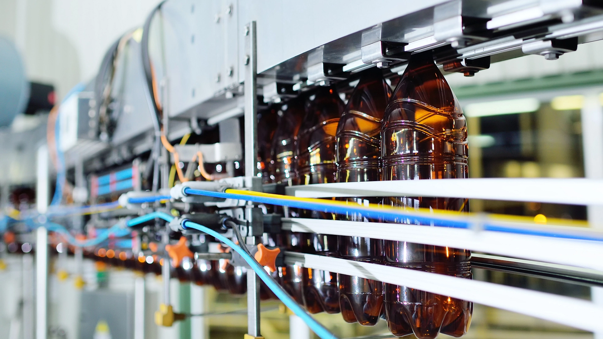 production of large-capacity plastic bottles for beverages, water and sunflower oil. Empty plastic PET bottles of yellow color on a conveyor belt.