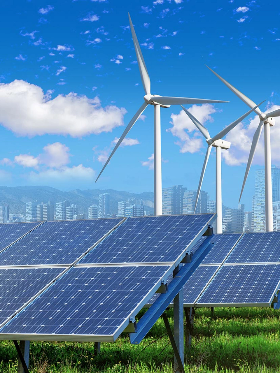 solar panels and wind turbines under blue sky and clouds with city on horizon