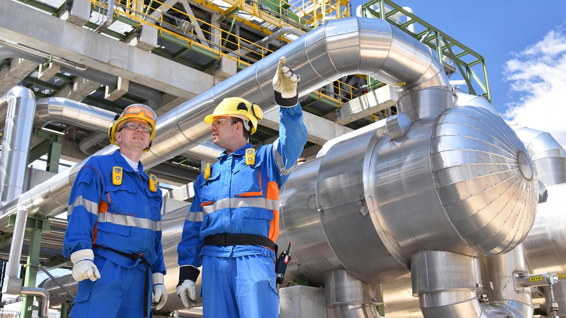 teamwork: group of industrial workers in a refinery - oil processing equipment and machinery