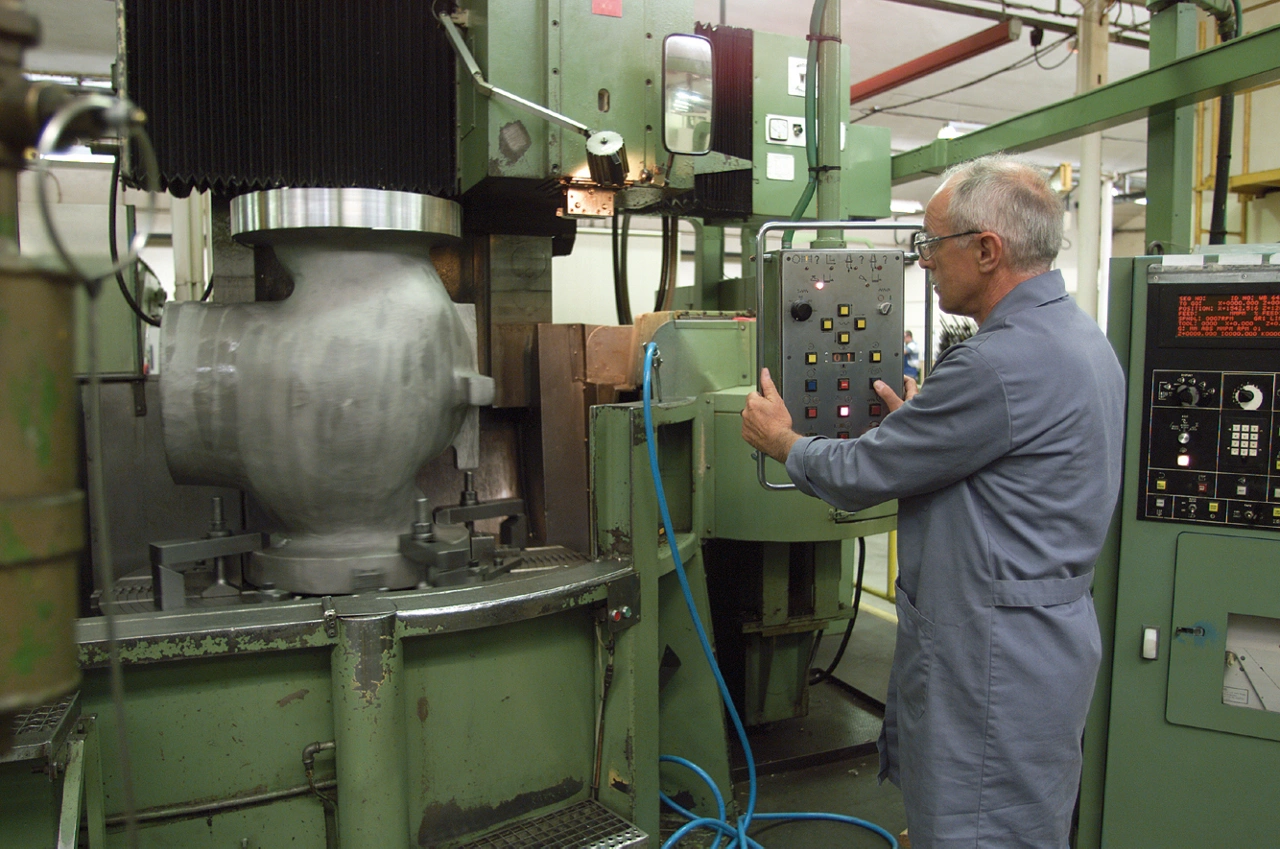 Engineer operating machine to produce large Fisher valve