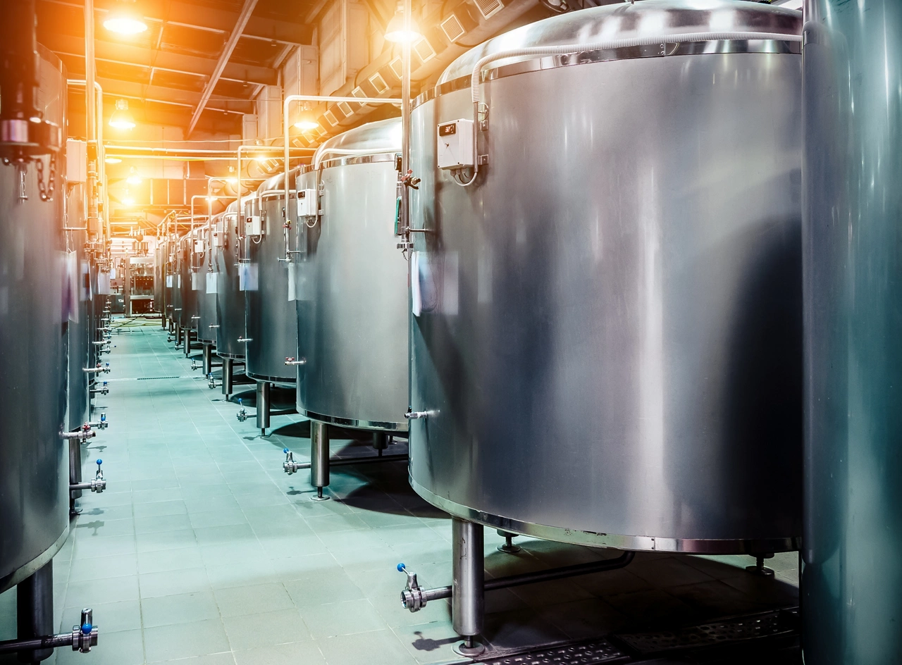 Modern Beer Factory. Rows of steel tanks for beer fermentation and maturation. Spot light effect